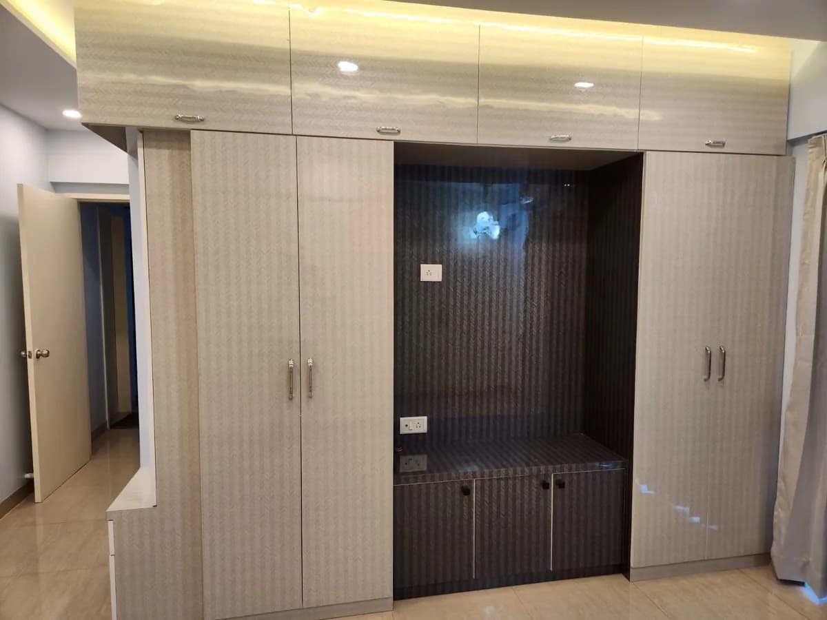 Floor-to-ceiling wooden wardrobe with loft storage and cove lighting — wardrobe design Pune